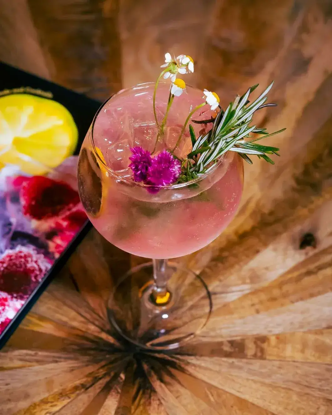 Overhead of a floral gin and tonic on a starburst wood table