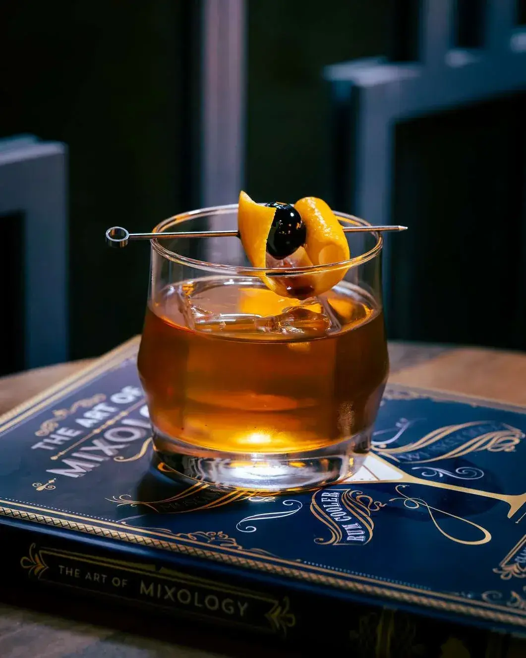Old fashioned with an orange twist and brandied cherry on a cocktail pick